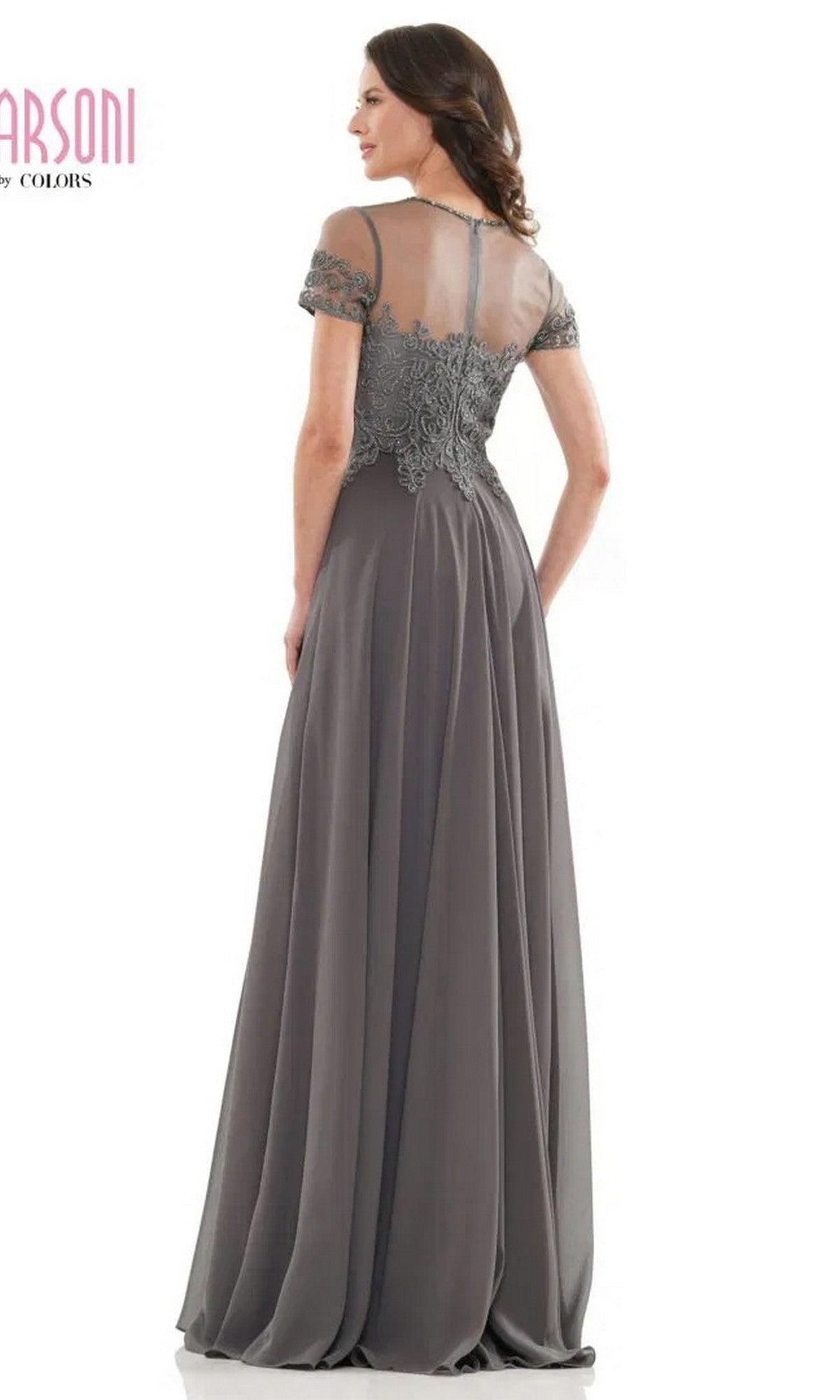 Woman wearing the Marsoni M271 long formal dress, featuring short sleeves, a lace-detailed bodice, chiffon pleated A-line skirt, and a sheer back panel, stands facing away from the camera.